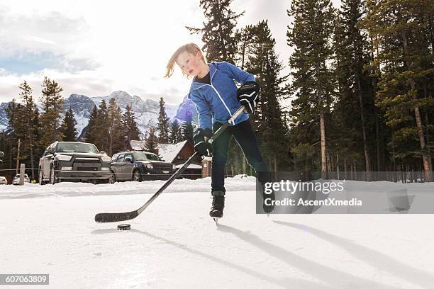 young boy palys hockey on commuinty pond,mountains - skater isolated stock pictures, royalty-free photos & images