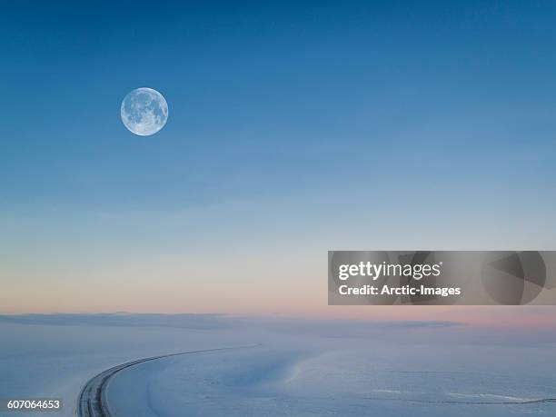 moon over snowy road, iceland - ciel bleu sans nuage photos et images de collection