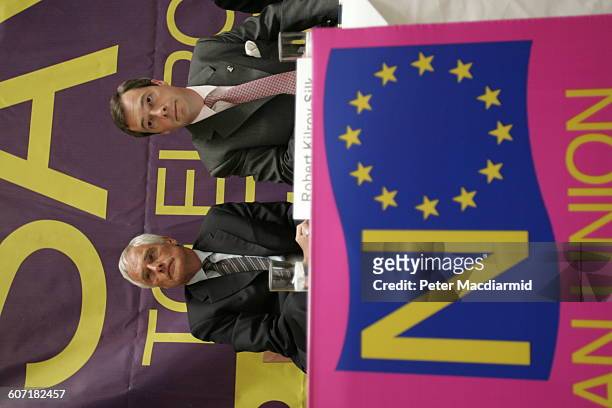 British politicians Robert Kilroy-Silk and Nigel Farage confer during a press conference, England, May 12, 2004. The banner behind them reads 'Say No...