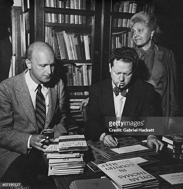 Welsh poet and writer Dylan Thomas signing one of his books for American poet and literary critic John Malcolm Brinnin , during a reception held in...