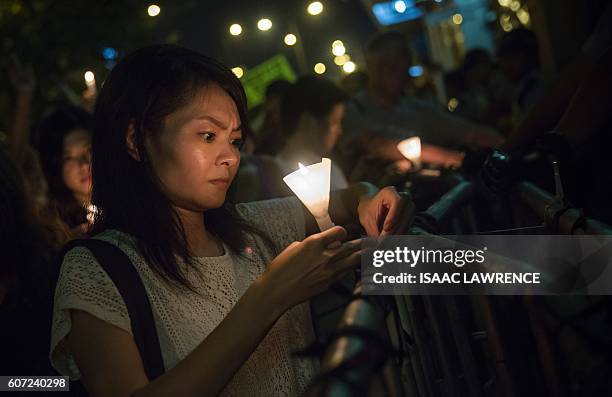 Protester ties a black ribbon to a barricade during a candle light vigile for the southern Chinese village of Wukan outside the Chinese Liason Office...