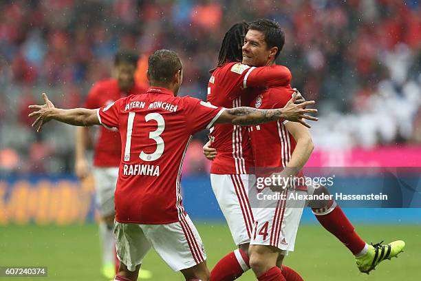 Xabi Alonso of Muenchen celebrates scoring the 2nd team goal with his team mate Renato Sanches and Rafinha during the Bundesliga match between Bayern...