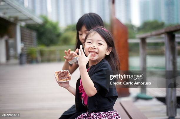 little sisters eating chocolate pastry. - child loves chocolates stock-fotos und bilder