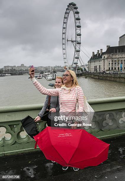 Tourists stop along Westminster Bridge near Big Ben on a rainy afternoon to take a selfie on September 11 in London, England. The collapse of Great...