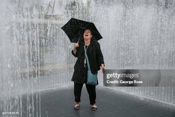 Woman holding an umbrella dances in an outdoor water fountain near the National Theatre as viewed on September 11 in London, England. The collapse of...