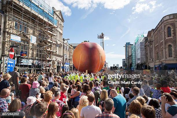 Members of the public gather to watch a giant peach as it is moved through the centre of Cardiff as part of a performance to mark the start of City...