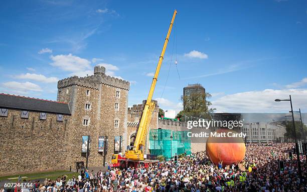 Members of the public gather in front of Cardiff Castle to watch a giant peach being moved through the centre of Cardiff as part of a street...