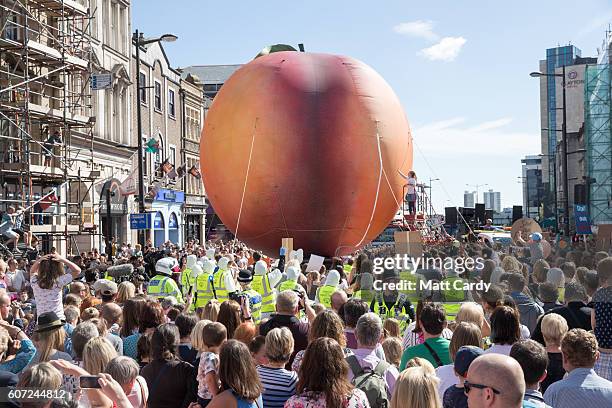 Members of the public gather to watch a giant peach as it is moved through the centre of Cardiff as part of a street performance to mark the start of...