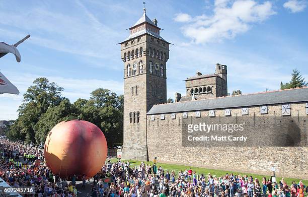 Members of the public gather in front of Cardiff Castle to watch a giant peach being moved through the centre of Cardiff as part of a street...