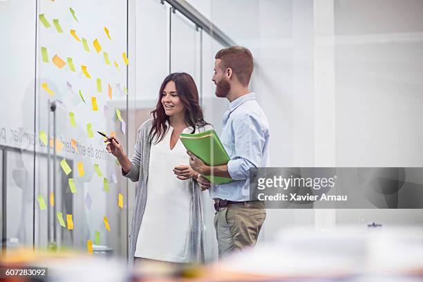 geschäftsleute, die sich klebenotizen im konferenzraum ansehen - team looking at adhesive notes in board room during meeting stock-fotos und bilder