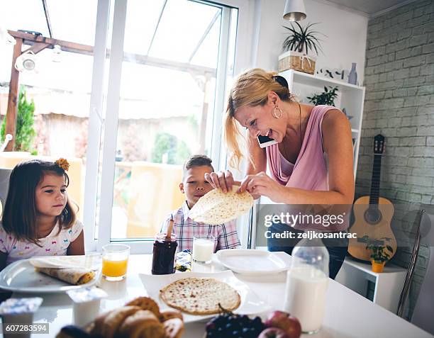 busy mother organizing children at breakfast in kitchen - busy mother stock pictures, royalty-free photos & images