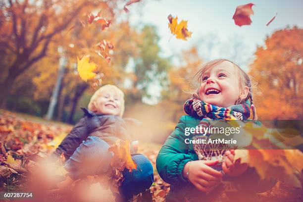 little boy and girl in autumn park - young leafs stockfoto's en -beelden