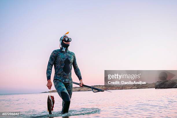 photo of a man coming back from spear fishing - man spear fishing stock pictures, royalty-free photos & images