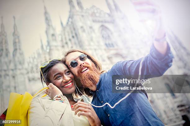 mixed race young cool couple taking selfie at duomo square - daily life at duomo square milan stockfoto's en -beelden