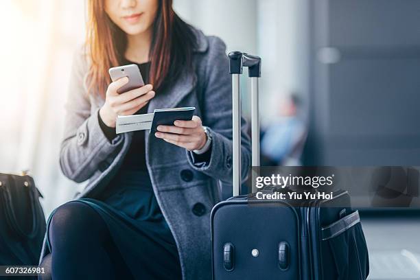 woman holding smartphone and passport at airport - plane ticket stock pictures, royalty-free photos & images