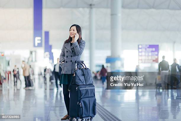 woman with suitcase using smartphone in airport - yiu yu hoi stock pictures, royalty-free photos & images