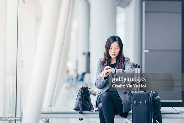 woman checking the time while waiting at airport - yiu yu hoi stock pictures, royalty-free photos & images