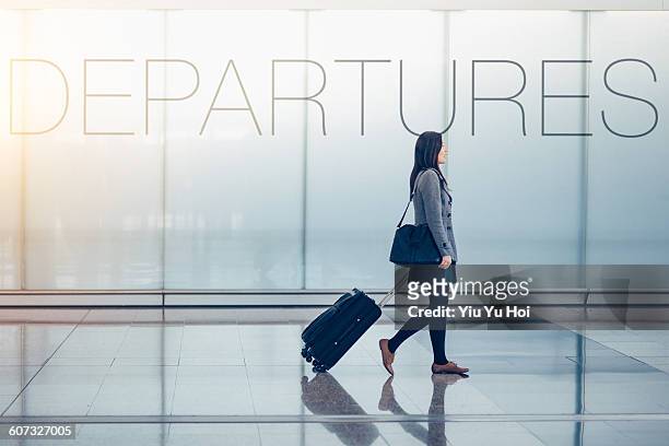 woman pulling suitcase in airport departures hall - wheeled luggage 個照片及圖片檔