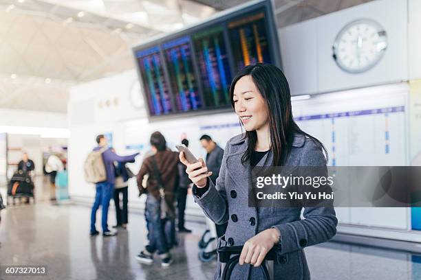 young woman using smartphone in airport concourse - yiu yu hoi stock pictures, royalty-free photos & images