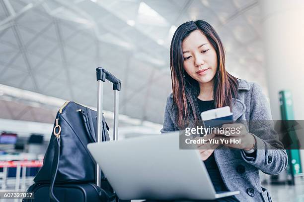 woman holding passport and using laptop at airport - yiu yu hoi stockfoto's en -beelden