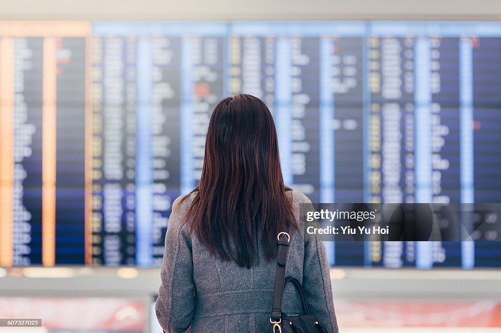 Woman looking up and checking schedule at airport