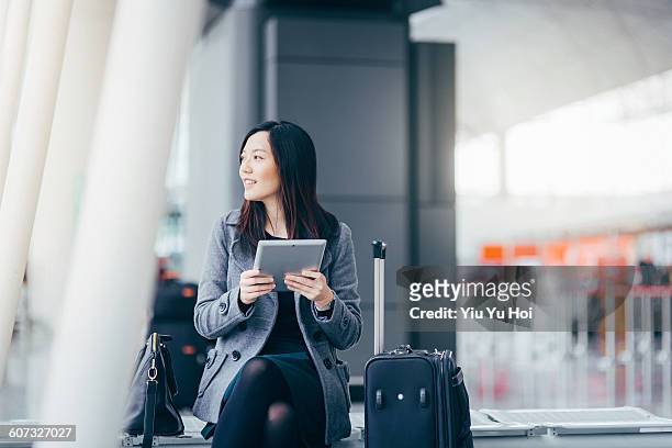 woman using digital tablet at airport terminal - flughafen menschen stock-fotos und bilder