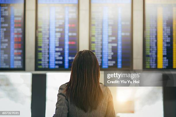 woman looking up and checking schedule in airport - yiu yu hoi stock pictures, royalty-free photos & images