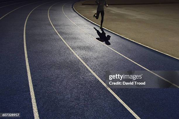 shadow of a runner on a running track - jogging track stock pictures, royalty-free photos & images