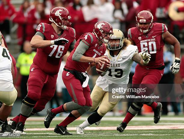 Quarterback Luke Falk of the Washington State Cougars carries the ball against Kevin Shelton of the Idaho Vandals while being guarded by Cody...