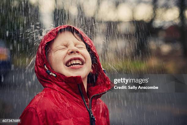 happy smiling boy in the rain - regenwetter stock-fotos und bilder