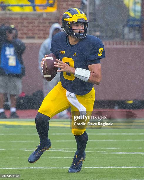 Quarterback John O'Korn of the Michigan Wolverines rolls out of the pocket and looks to make a play during a college football game against the UCF...