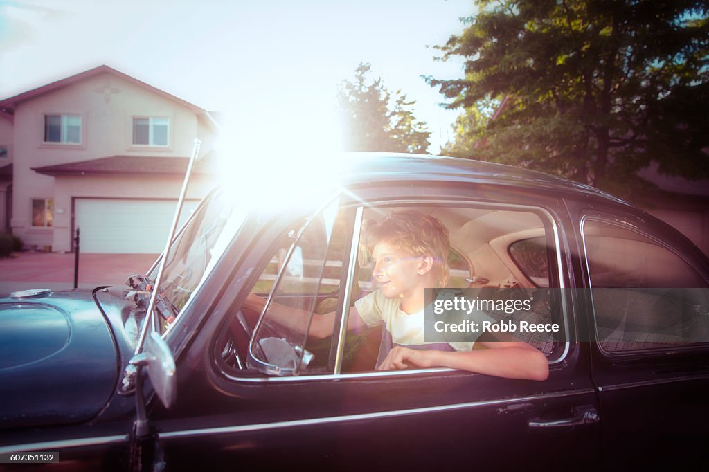 A young man driving along a suburban street