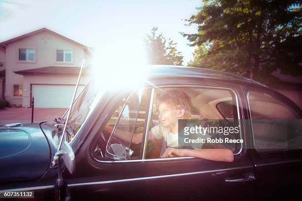 a young man driving along a suburban street - robb reece stock pictures, royalty-free photos & images