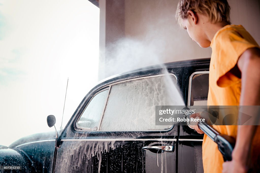 A young boy washing a 1967 vintage Volkswagen Bug at a carwash