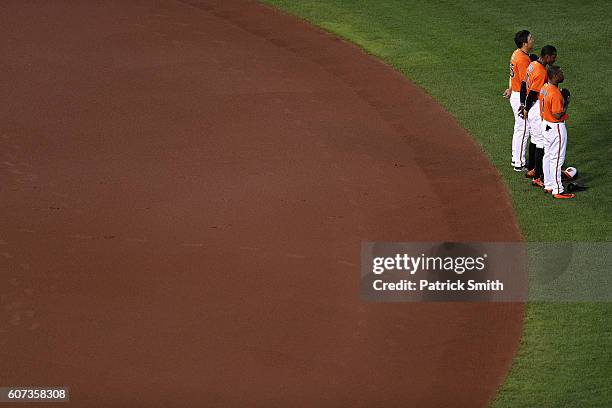 Hyun Soo Kim, Adam Jones and Michael Bourn of the Baltimore Orioles stand during the national anthem before playing against the Tampa Bay Rays at...