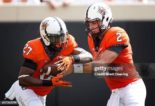 Quarterback Mason Rudolph hands off to running back Justice Hill of the Oklahoma State Cowboys during the game against the Pittsburgh Panthers...