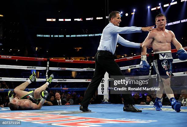 Canelo Alvarez, right, is lead to his corner after knocking down Liam Smith, left, during the WBO Junior Middleweight World fight at AT&T Stadium on...