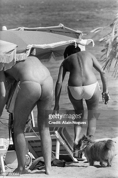 Partially nude couple sunbathes on a St.-Tropez Beach. The man on the left wears a g-string and the woman at right is wearing bikini briefs.