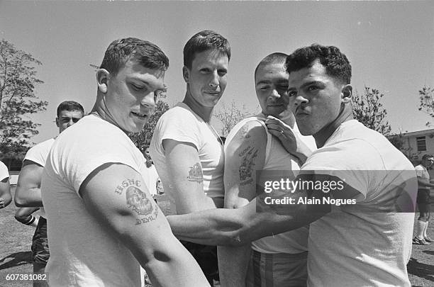 Four U.S. Marines show their tattooed arms. 10,000 Marines stationed in Okinawa are getting ready to be sent to the Indian Ocean.