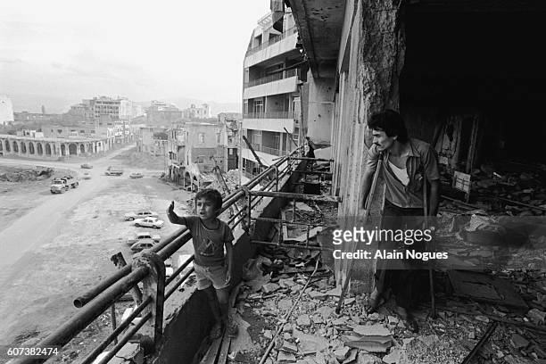 Young boy and his wounded father inspect the bombed out shell of their apartment in Beirut. The ruins testify to the intense fighting going on in the...