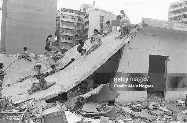 Beirut children play and slide on the roof a collapsed house. The ruins testify to the intense fighting going on in the city since June 1982 as a...