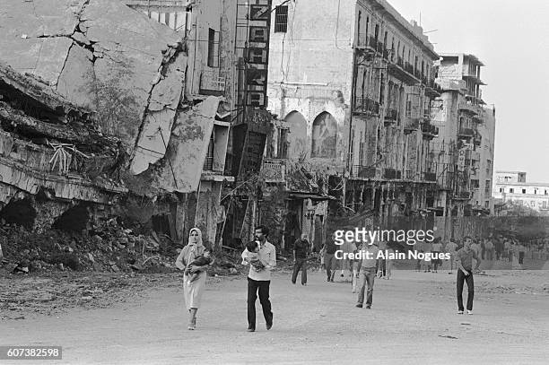 People of Beirut stroll along destroyed and damaged buildings. The ruins testify to the intense fighting going on in the city since June 1982 as a...