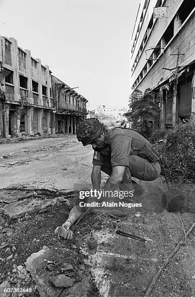 French paratrooper on a mine-clearance mission has found a mortar shell in a Beirut street. The ruins testify to the intense fighting going on in the...