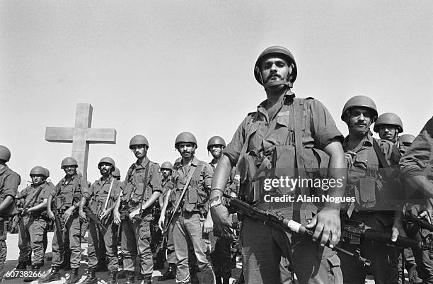 Soldiers of the Kataeb phalanx pose in front of a large crucifix. | Location: Lebanon.