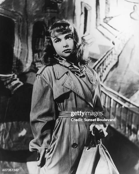 French actress Francoise Arnoul holds a revolver on the set of "L'Epave," directed by Willy Rozier.