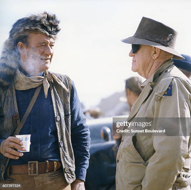 American actors and director John Wayne, while directing his movie The Alamo near Brackettville, Texas, visits with veteran director and Wayne mentor...