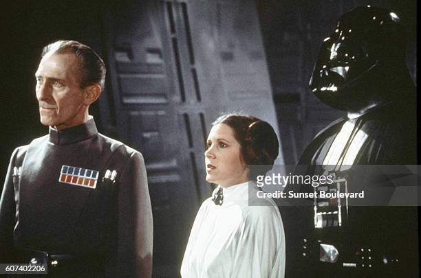 British actors Peter Cushing, David Prowse, and American actress Carrie Fisher on the set of Star Wars: Episode IV - A New Hope written, directed and...