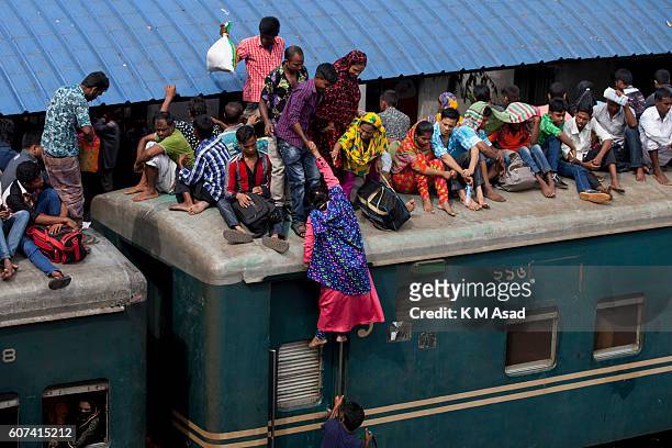 Woman try to go roof top and take risk to travel their villages, ahead of the Eid Al-Adha celebrations at the Airport Railway Station in Dhaka....