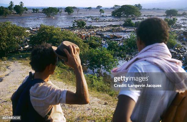 Two men look out over a field of mud, where a lahar from the erupting Nevado del Ruiz volcano flowed into a valley in Colombia. The 1985 eruption...