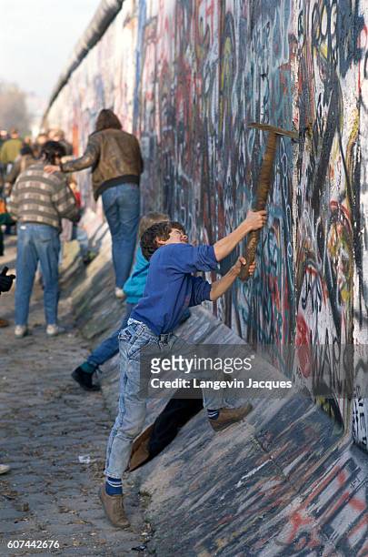 Boy welds a pickaxe to participate in the destruction of the Berlin Wall, between the Postdam Platz and the Brandenburg Gate. The Berlin Wall...